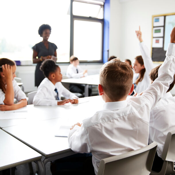 High,School,Students,Wearing,Uniform,Raising,Hands,To,Answer,Question Classroom of students